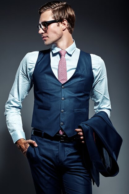 Modelo masculino elegante elegante joven del hombre de negocios en traje azul y gafas de moda, posando en estudio