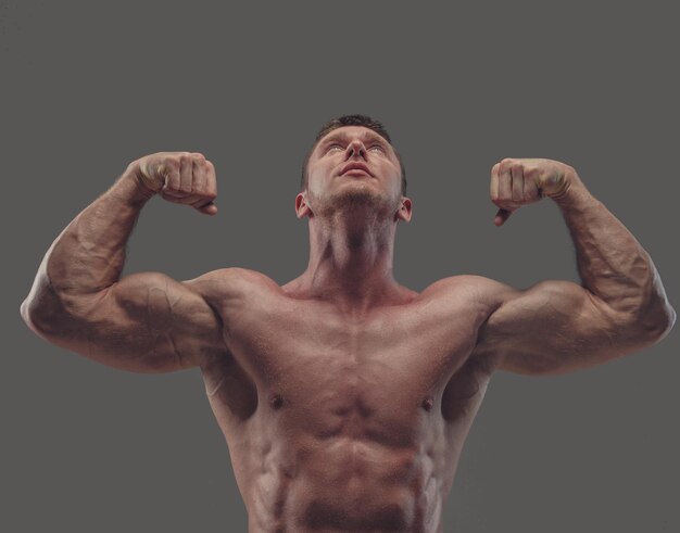 Modelo masculino de fitness sin camisa bronceado aislado en un fondo gris.