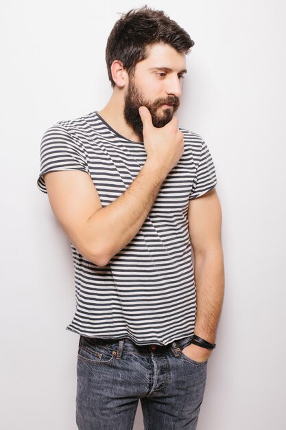 Modelo masculino joven barbudo sonriente vestido casualmente, aislado sobre la pared blanca.