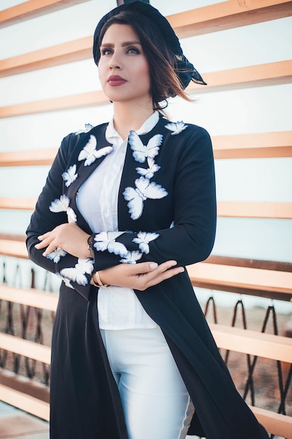 Modelo de moda en chaqueta de punto negro con mariposas y jeans blancos