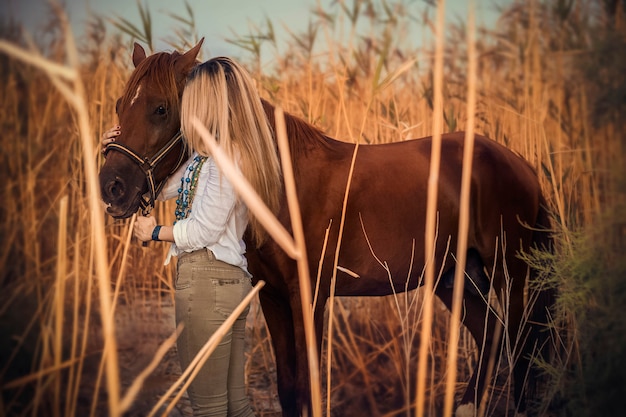 Modelo de moda en vestido blanco caminando con un caballo