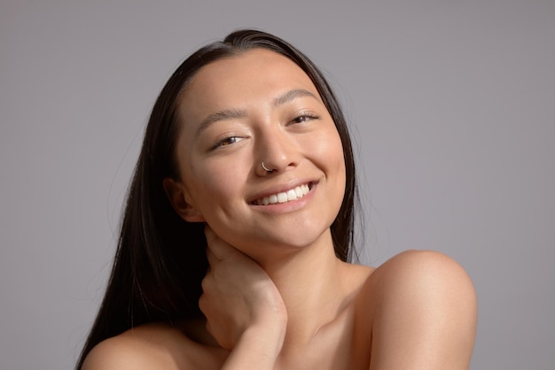 Modelo morena sonriente feliz en estudio con piel estroboscópica brillante ideal