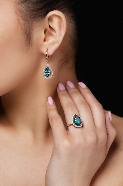 Modelo muestra pendientes y anillo con hermosas piedras preciosas azules