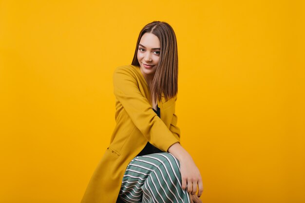 Modelo de mujer adorable en chaqueta brillante posando con una sonrisa sincera. glamorosa mujer caucásica en ropa amarilla.