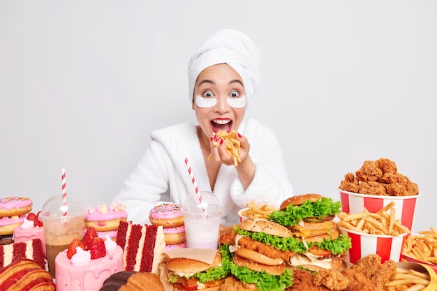 Modelo de mujer asiática positiva come papas fritas consume comida chatarra