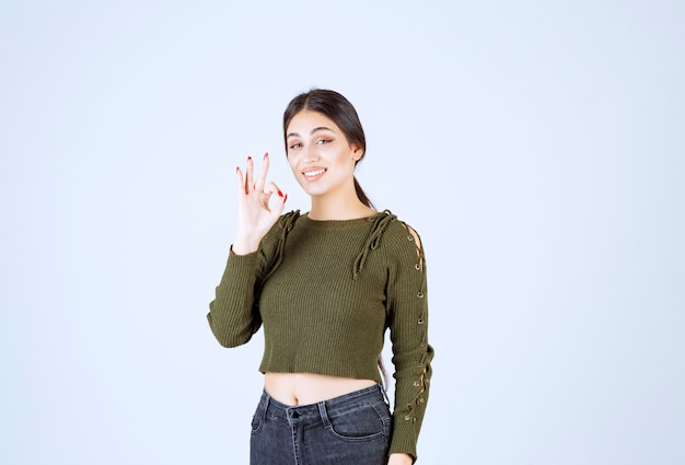 Un modelo de mujer bonita joven guiñando un ojo y mostrando un gesto aceptable.