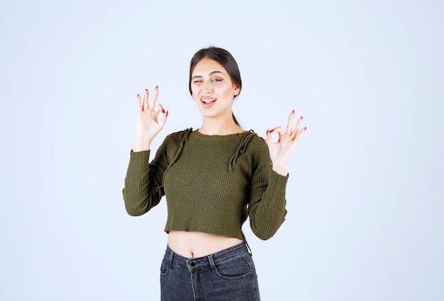 Un modelo de mujer bonita joven guiñando un ojo y mostrando gestos aceptables.