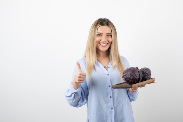 modelo de mujer bonita sonriente con repollo mostrando un pulgar hacia arriba.