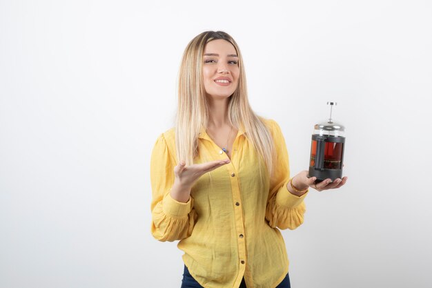 modelo de mujer bonita sonriente sosteniendo una tetera.