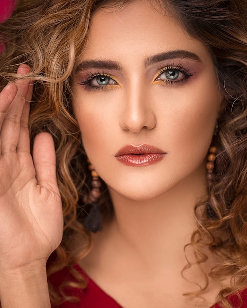 Modelo de mujer con cabello rubio rizado y maquillaje elegante