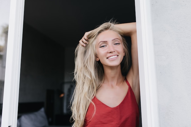 Modelo de mujer caucásica extática posando temprano en la mañana con una sonrisa sincera. Mujer guapa romántica en pijama rojo divirtiéndose.