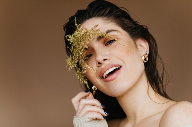 Modelo de mujer caucásica refinada posando con planta y sonriendo Primer plano de una linda chica europea con cabello negro