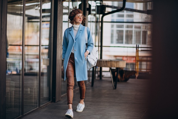 Modelo de mujer joven en abrigo azul por el café