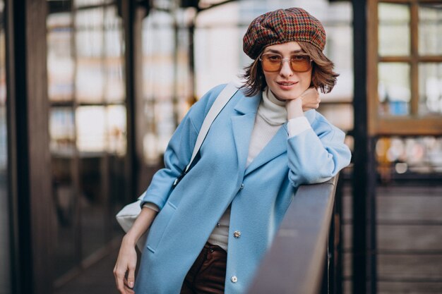 Modelo de mujer joven en abrigo azul por el café
