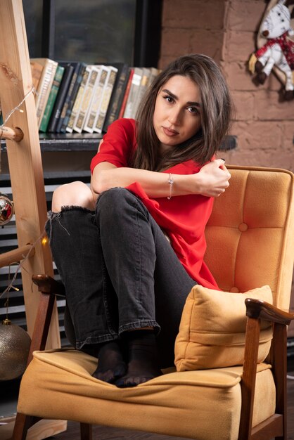 Un modelo de mujer joven en blusa roja sentada y posando.