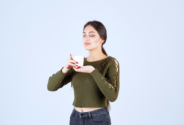 Un modelo de mujer joven y bonita sosteniendo un vaso de plástico con bebida caliente.