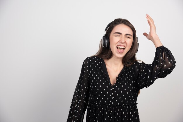 Modelo de mujer joven cantando y escuchando música en auriculares