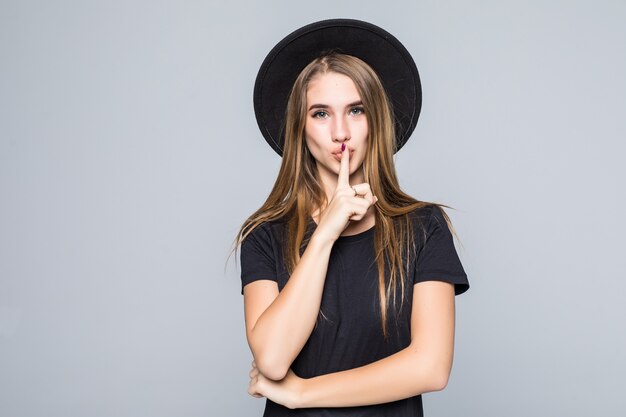 Modelo de mujer joven hermosa muestra emociones dejar de hablar callarse vestida con ropa oscura aislada sobre fondo gris