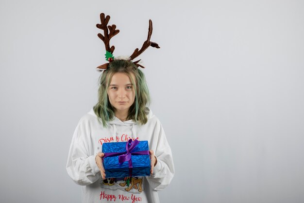 modelo de mujer joven con máscara de cuernos de ciervo sosteniendo un regalo.