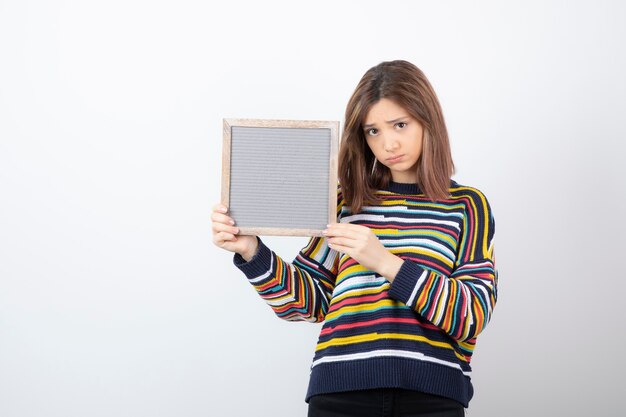 modelo de mujer joven de pie y apuntando a un marco.