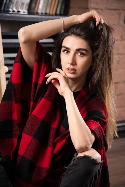 Modelo de mujer joven posando con cuadros escoceses cerca de bolas de Navidad.