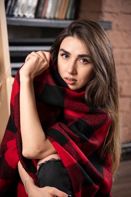 Modelo de mujer joven posando con cuadros escoceses cerca de bolas de Navidad.