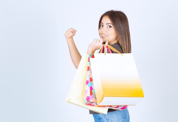 Una modelo de mujer joven que lleva sus bolsas de la compra y las señala.