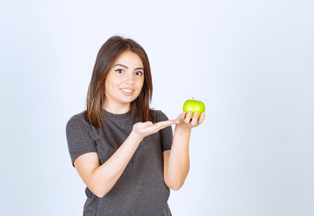 modelo de mujer joven que muestra en una manzana verde