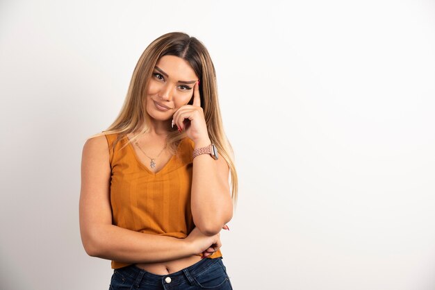 Modelo de mujer joven en ropa casual posando sobre fondo blanco.