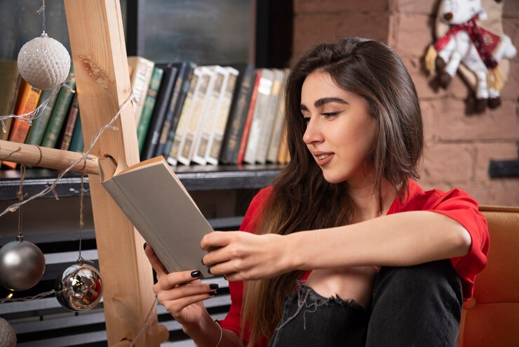 Foto gratuito un modelo de mujer joven sentada y leyendo un libro.