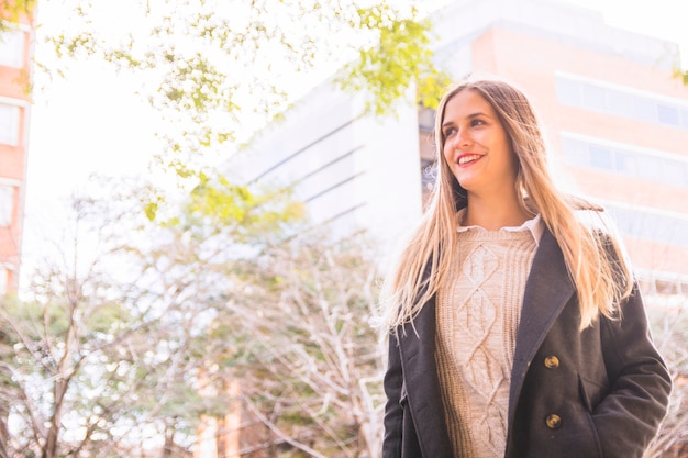 Foto gratuita modelo de mujer joven sonriendo en edificio urbano fondo brillante