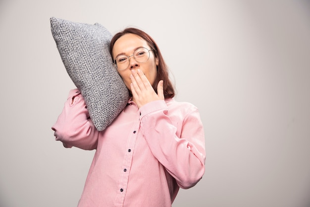 Modelo de mujer joven sosteniendo una almohada sobre un fondo blanco. Foto de alta calidad