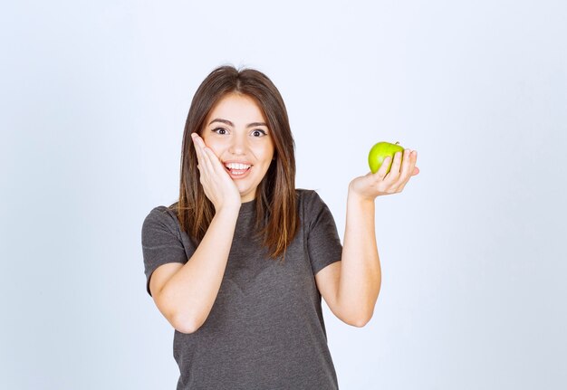 modelo de mujer joven sosteniendo una manzana verde.