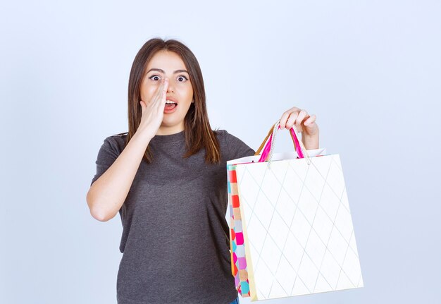 Un modelo de mujer joven sosteniendo un montón de bolsas de la compra sobre fondo blanco.