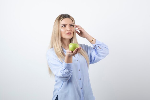 modelo de mujer muy atractiva de pie y sosteniendo una manzana verde fresca.