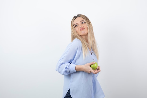 modelo de mujer muy atractiva de pie y sosteniendo una manzana verde fresca.