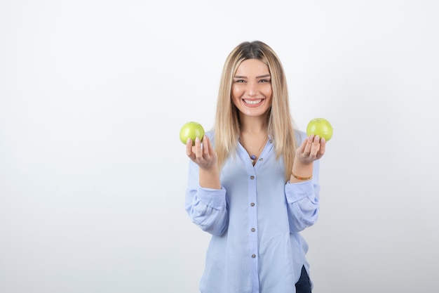 modelo de mujer muy atractiva de pie y sosteniendo manzanas frescas.