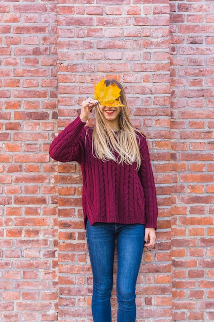 Modelo de mujer sin rostro que mira aunque hoja de otoño