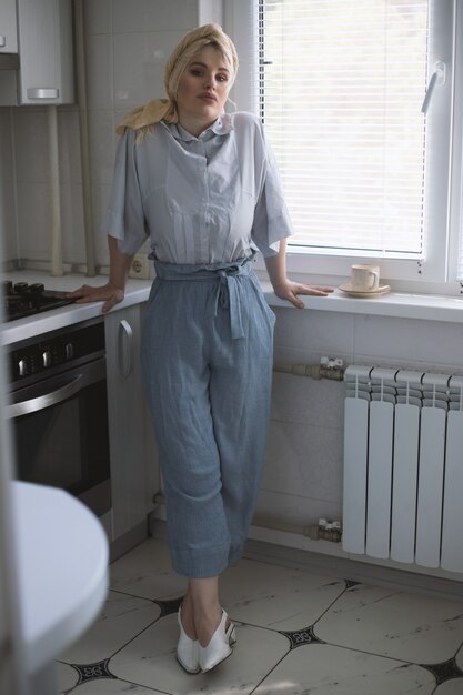 Modelo de mujer rubia atractiva en la cocina disfrutando de una taza de té