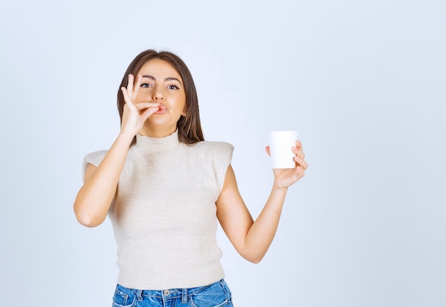 Un modelo de mujer sonriente mostrando un vaso de plástico y posando.