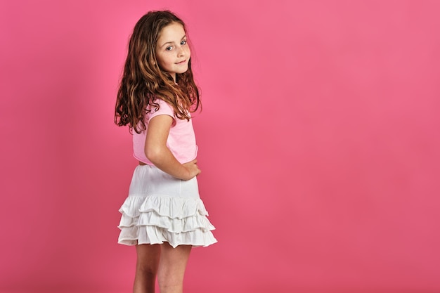 Foto gratuita modelo de niña posando en una pared rosa