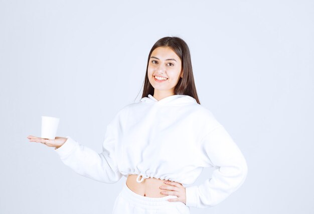 modelo de niña sonriente sosteniendo un vaso de plástico.