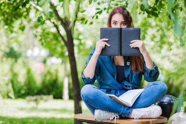 Modelo posando con libros en el parque