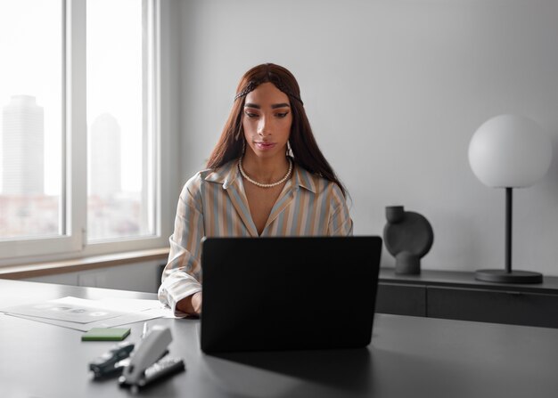 Modelo queer de tiro medio que trabaja con una computadora portátil