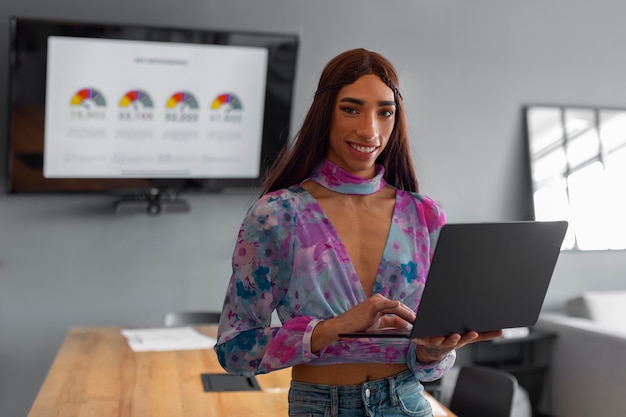 Modelo queer de tiro medio que trabaja con una computadora portátil