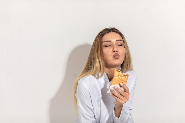 Modelo rubia mordiendo un sándwich y disfrutando