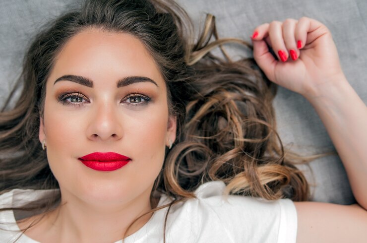 Modelo sensual de la mujer con el pelo azotado por el viento pelo moreno sobre fondo gris claro. Peinado largo brillante de la salud. Belleza y cuidado del cabello. Maquillaje natural de la manera