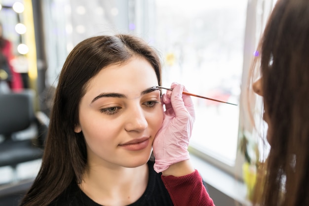 Modelo sonriente está haciendo procedimiento de pintura de cejas