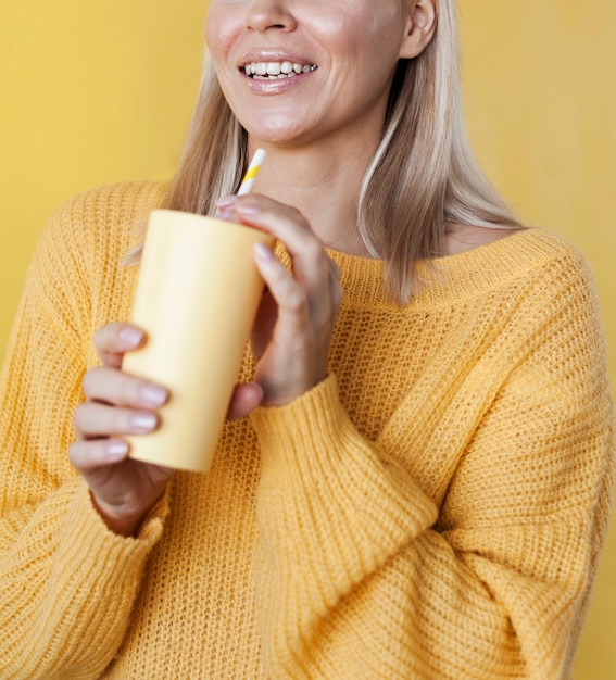 Modelo sonriente que sostiene la bebida amarilla