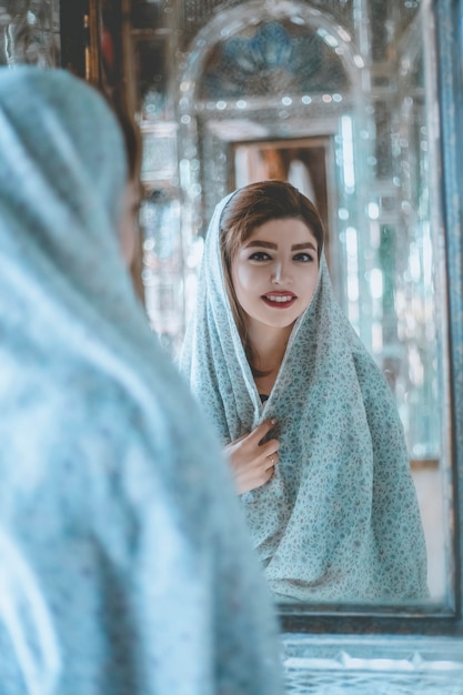 Foto gratuita modelo en trajes de oración frente a una mezquita histórica frente al espejo